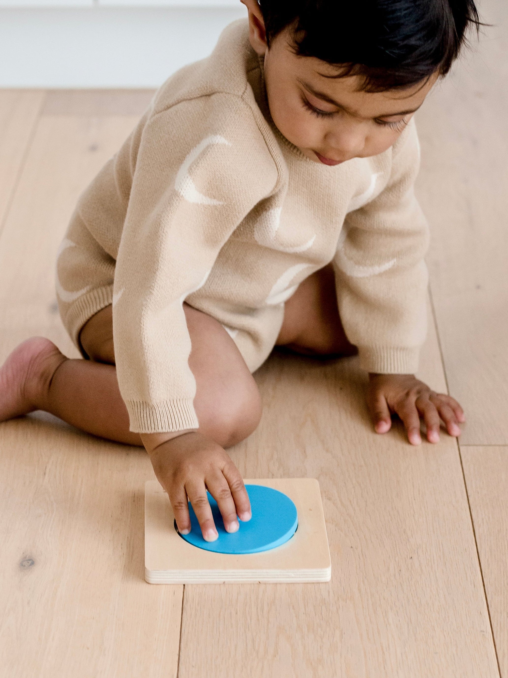 Toddler playing with Totli blue circle mirror puzzle on floor