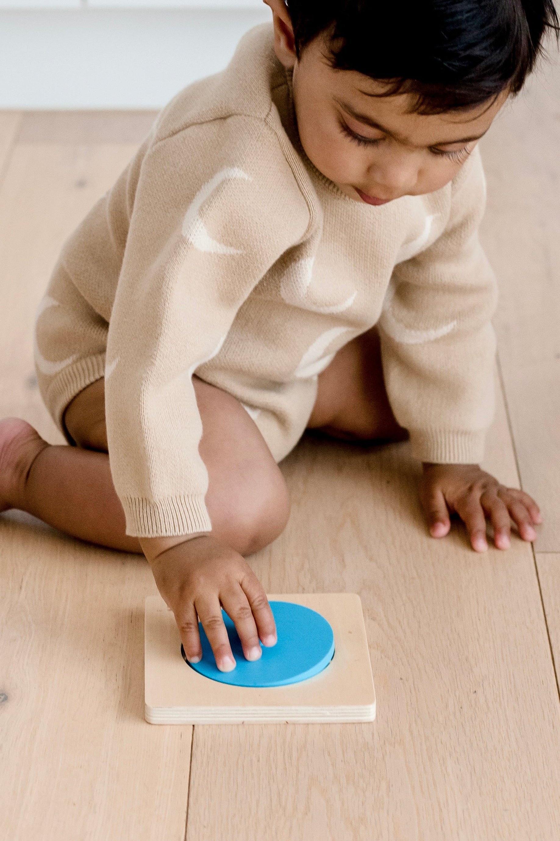Toddler playing with Totli blue circle mirror puzzle on floor
