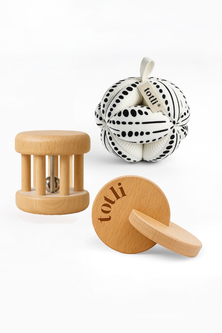 Totli Montessori play set including an organic cotton ball, wooden rolling rattle and wooden hand to hand disks
