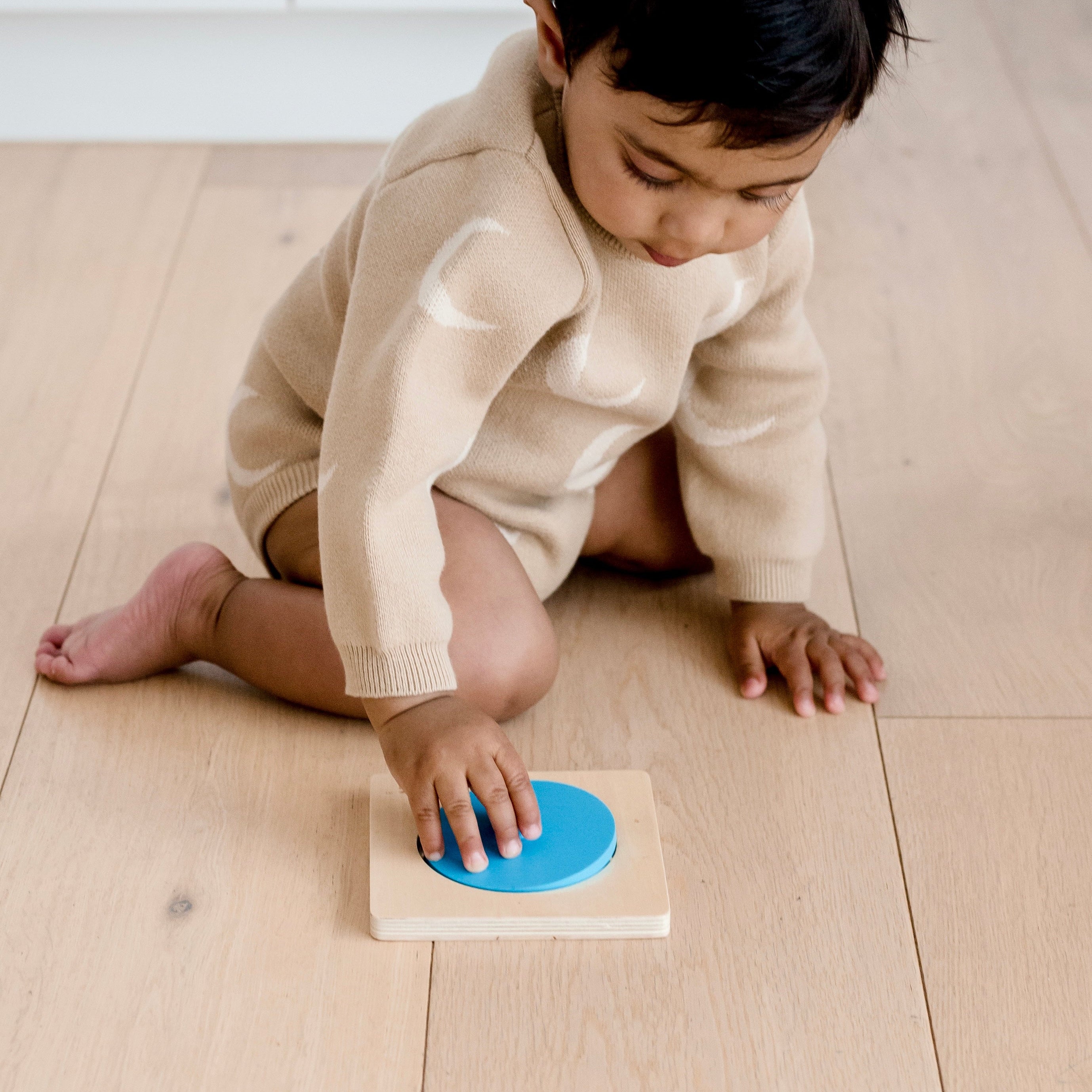 Toddler playing with Totli blue circle mirror puzzle on floor