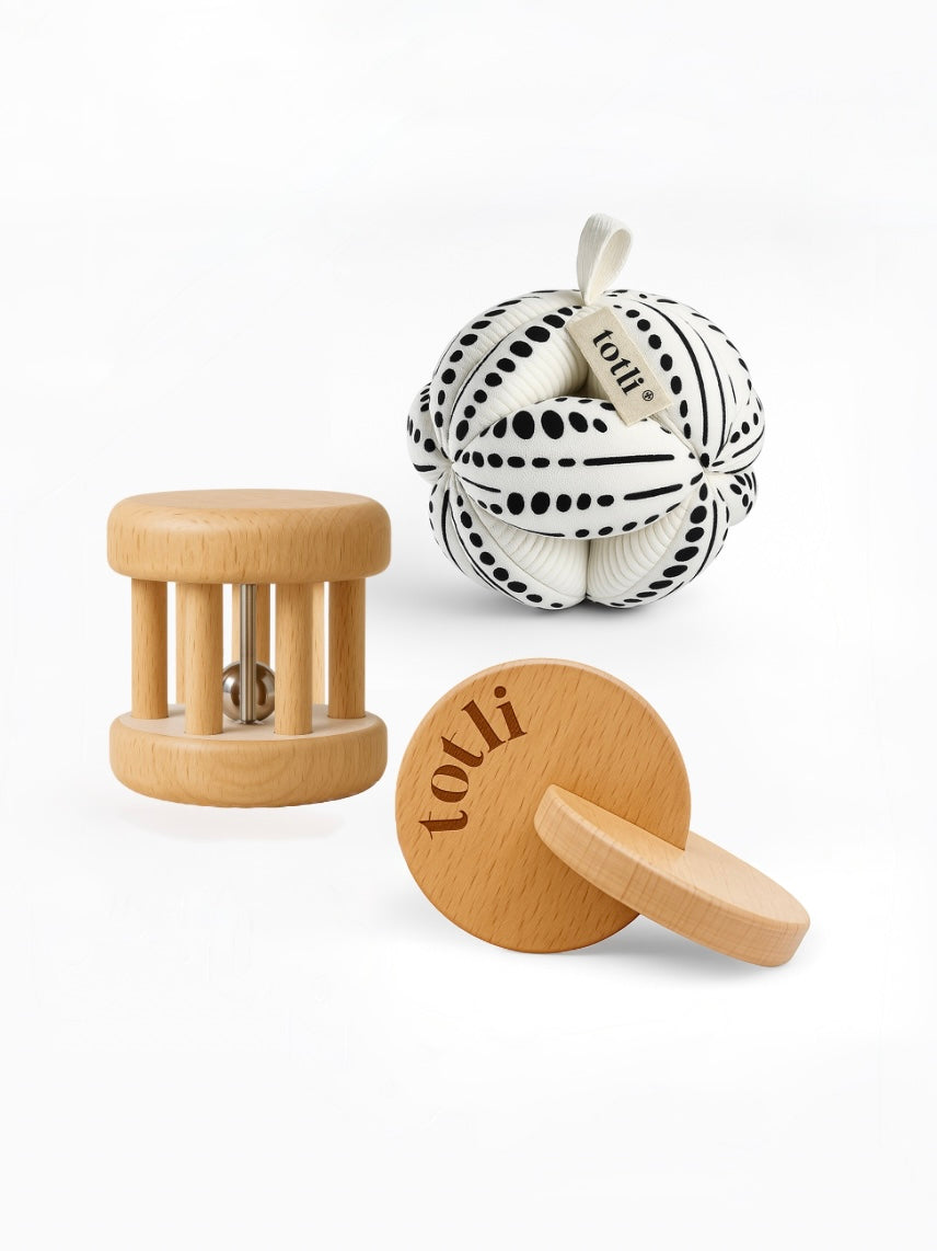 Totli Montessori play set including an organic cotton ball, wooden rolling rattle and wooden hand to hand disks